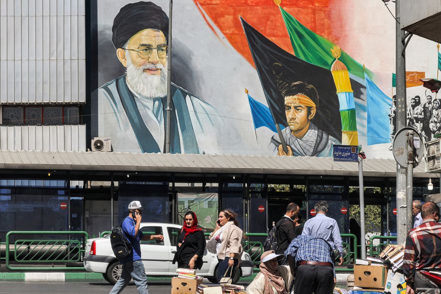 Des personnes marchent dans le centre de Téhéran devant une peinture murale de l'actuel guide suprême de l'Iran, l'ayatollah Ali Khamenei, le 10 septembre 2023