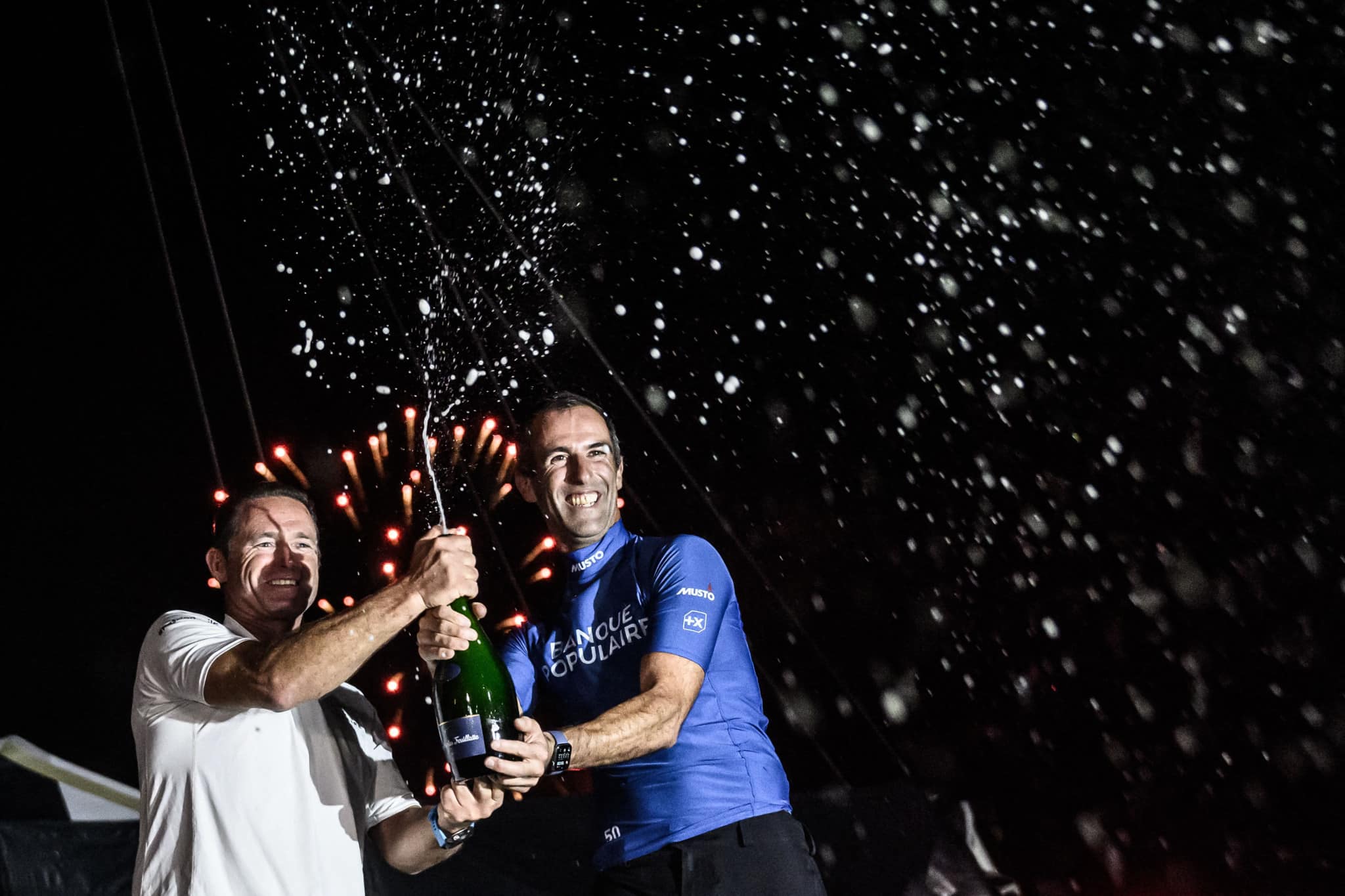 TOPSHOT - French skipper of the Banque Populaire Ultim multihull Armel Le Cleac'h (R) sprays Champagne with his co-skipper Sebastien Josse as they celebrate after winning the Transat Jacques Vabre pair sailing race, from Le Havre to the French overseas island of La Martinique, in Fort-de-France in the west indies island of Martinique on November 12, 2023. (Photo by LOIC VENANCE / AFP)
